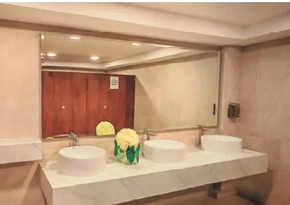 Baño terminado con mesón de mármol y tres lavamanos tras la remodelación
